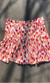 Mini jupe Noa. Coco Pastilles. Rouge corail. Jersey imprimé, plissée